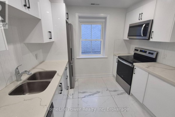 White kitchen with stainless steel appliances, double sink, and white quartz countertops. - 1u - 35 Wellington Street, Brantford