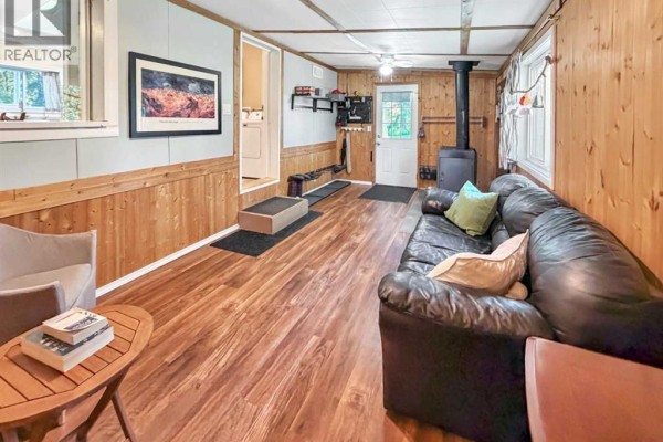 Bedroom with a single bed, nightstand, and window overlooking trees. - 2,  Spruce Park, Rural Clearwater County