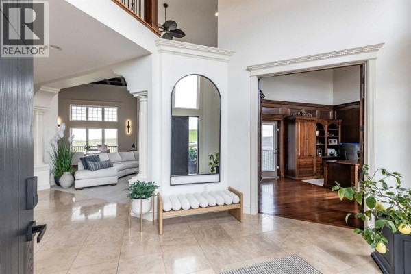 Foyer with marble tile flooring, a large mirror, a bench, and an archway leading to a living area. - 2, 12016 Range Road 61a, Rural Cypress County