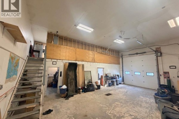 Wide shot of a large workshop space with a garage door, metal stairs, and unfinished upper level. - 2, 162 Hampshire Road, Hinton