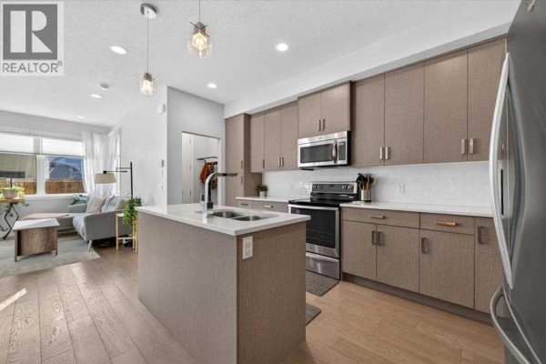 Open-concept kitchen with a large island and adjacent living area. - 2, 1920 25a Street Sw, Calgary