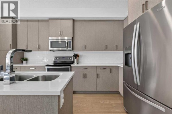 Stainless steel refrigerator and modern cabinetry in a spacious kitchen. - 2, 1920 25a Street Sw, Calgary