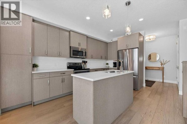 Contemporary kitchen with light wood floors and a central island. - 2, 1920 25a Street Sw, Calgary