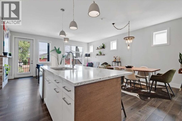 Spacious living and dining area with a kitchen island, dining table, and seating area. - 2, 1936 25a Street Sw, Calgary