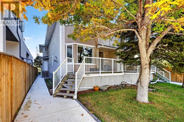 Exterior of a townhouse with a wooden fence and grass. - 2, 2811 24a Street Sw, Calgary