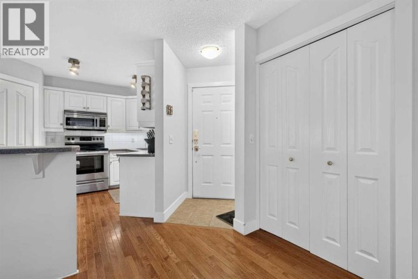 View of the entrance area and kitchen with white cabinets and wood floors. - 2, 2811 24a Street Sw, Calgary
