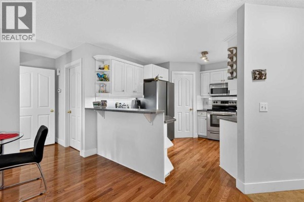 Kitchen with white cabinets, stainless steel appliances, and a breakfast bar. - 2, 2811 24a Street Sw, Calgary