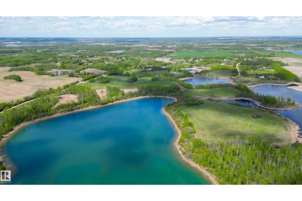 Aerial view of a large, bright turquoise lake with green tree-lined shores and distant fields. - 2, 52313 Twp Rd 24, Rural Parkland County