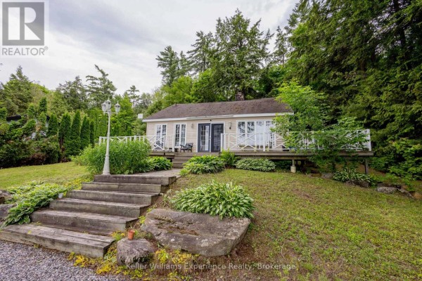 Front view of a cottage with a long wooden staircase and landscaping. - 2 - 1018 Georgina Way, Gravenhurst)