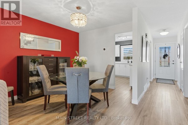 Renovated dining room with glass table, chandelier, and modern kitchen view - 2 - 110 Silvan Drive, Welland