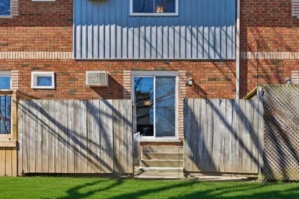 Rear of brick and siding building with sliding door, stairs, yard, fence, AC units - 2 - 110 Silvan Drive Welland