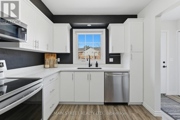 Modern kitchen with white cabinets, black sink, stainless appliances, and window - 2 - 110 Silvan Drive, Welland