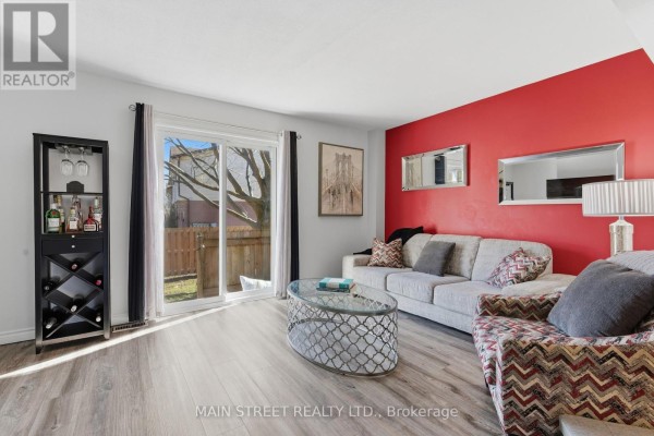 Living room with sliding glass doors, laminate flooring, and red accent wall - 2 - 110 Silvan Drive, Welland