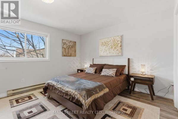 Modern bedroom with bed, nightstands, window, and hardwood floors - 2 - 110 Silvan Drive, Welland