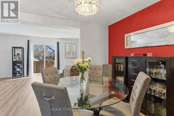 Modern dining room with glass table, chandelier, and vinyl plank flooring - 2 - 110 Silvan Drive, Welland