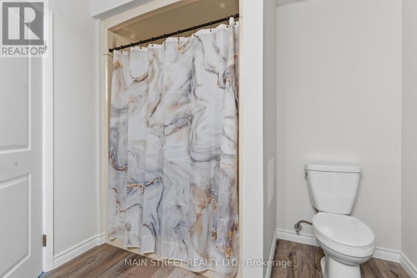 Renovated bathroom with toilet, shower curtain, and wood-look flooring - 2 - 110 Silvan Drive, Welland