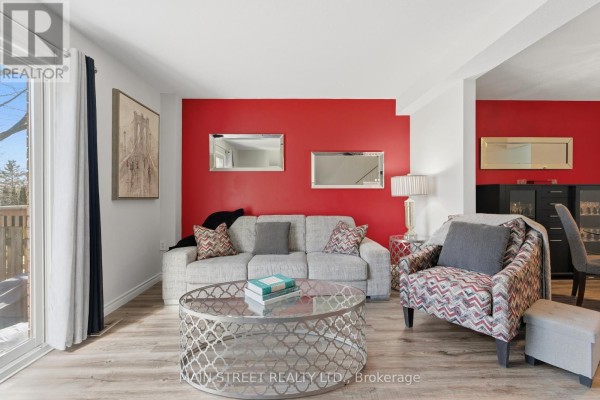 Living room with laminate flooring, red accent wall, and sliding door - 2 - 110 Silvan Drive, Welland