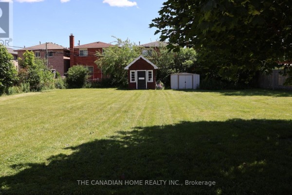 Large grassy backyard with a small red shed and a white shed. - 2 - 113 Pitfield Road, Toronto