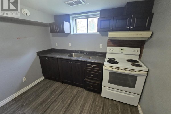 Small kitchen with dark wood cabinets, grey countertop, and white stove. - 2 - 113 Pitfield Road, Toronto