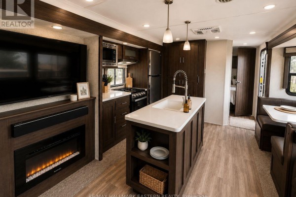 Interior view of RV kitchen and living area with fireplace, island, and dark wood cabinets. - #2 - 1280 Gail Park Drive N, Selwyn
