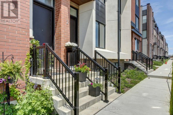 Front entrance of a townhouse with brick facade, black railings, and steps lined with plants. - 2 - 130 Frederick Tisdale Drive, Toronto