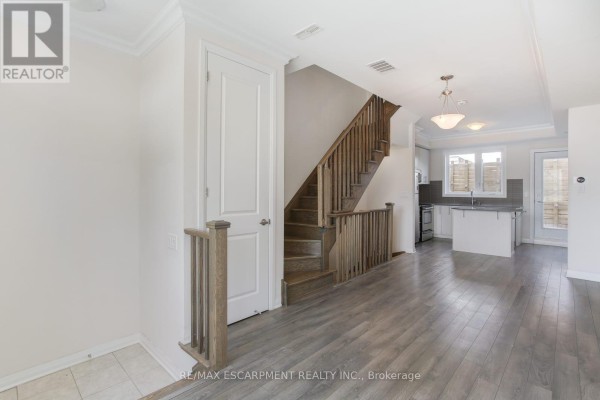 Interior view of a townhouse showing a staircase, white doors, and open concept living area. - 2 - 130 Frederick Tisdale Drive, Toronto