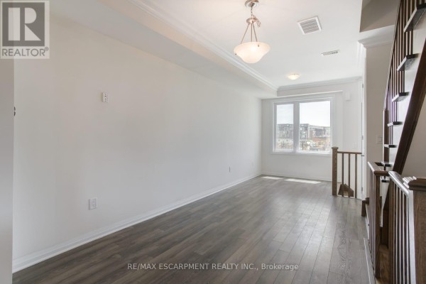 Bright living area in a townhouse with light gray laminate flooring and a large window. - 2 - 130 Frederick Tisdale Drive, Toronto