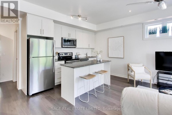 View of the kitchen island with granite countertop, and seating, facing the living room. - 2 - 130 Long Branch Avenue, Toronto