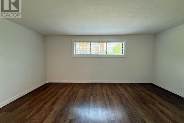 Hallway with stacked white washer and dryer, white doors, and a view into a bedroom. - 2 - 171 Huron Street, Guelph