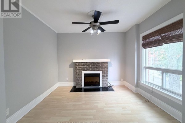 Living room with grey walls, a brick fireplace, wood flooring, and a window with blinds. - 2 - 189 Stinson Street, Hamilton