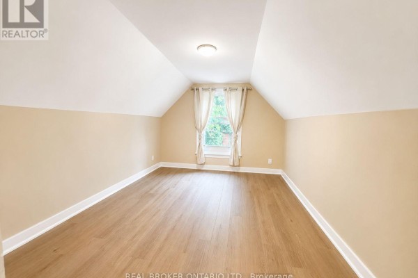 Empty room with vaulted ceiling, wood flooring, and a window with curtains. - 2 - 189 Stinson Street, Hamilton