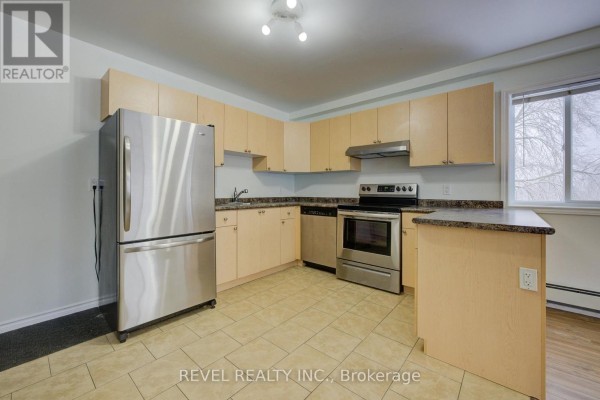 Stainless steel refrigerator and appliances in a kitchen with light wood cabinets. - 2 - 20 Puleston Street, Brantford
