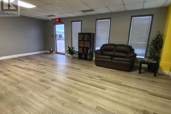 Interior view of a reception area with light wood floors, leather sofa, and windows. - 2 - 2134 Crumlin Side Road, London East
