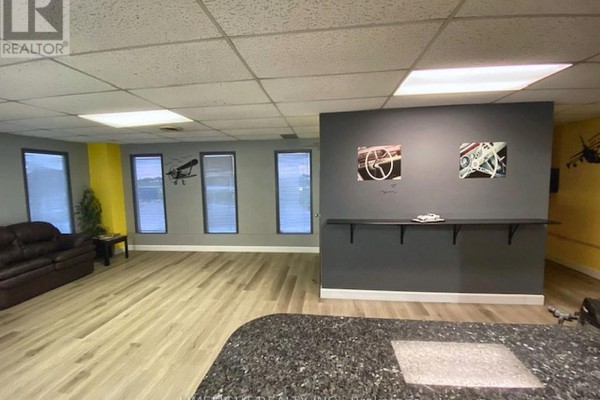 Interior view of a reception area with a grey counter, windows, and artwork on the wall. - 2 - 2134 Crumlin Side Road, London East