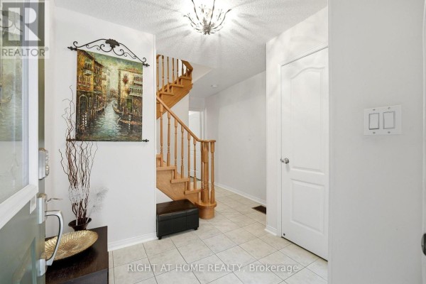Tiled entryway with a staircase, artwork, and white doors. - 2 - 23 West Deane Park Drive, Toronto