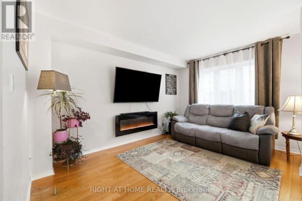 Living room featuring a grey sofa, electric fireplace, large television, and hardwood floors. - 2 - 23 West Deane Park Drive, Toronto