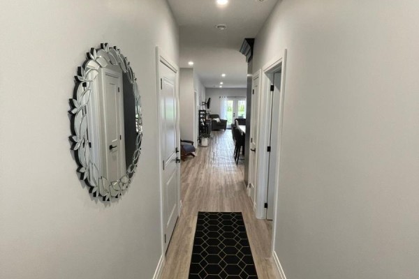 A long, neutral-colored hallway with light wood floors, white doors, and a decorative mirror. - 2 - 255 Albert Street, Huron East