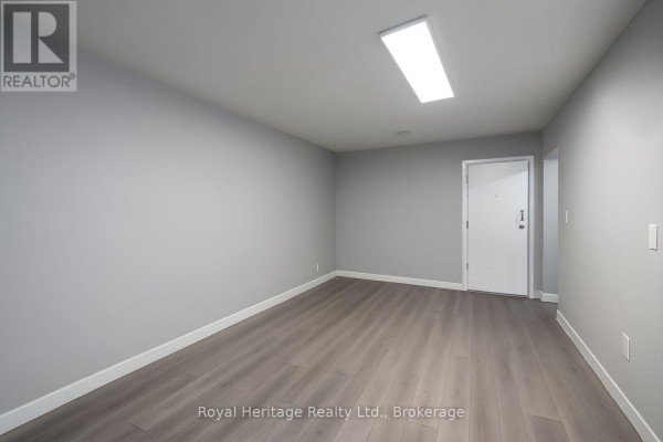 Living room interior with grey walls, laminate flooring, and a white door. - 2 - 264 Division Street, Cobourg