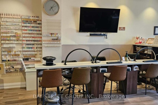 Nail salon reception desk with chairs, multiple polish bottles on shelves, and a TV. - 2 - 2671 Bur Oak Avenue, Markham
