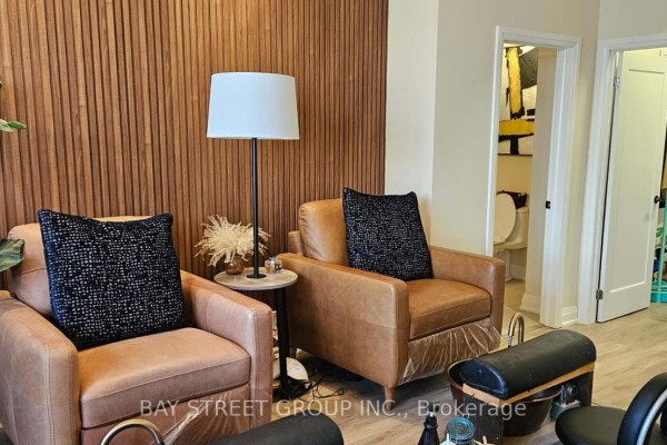 Two leather chairs with pillows and a floor lamp next to a wooden accent wall. - 2 - 2671 Bur Oak Avenue, Markham