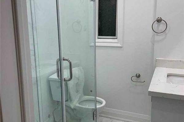 A bathroom with a glass-enclosed shower, white toilet, and vanity with a white marble countertop. - 2 - 271 Dunn Avenue, Toronto