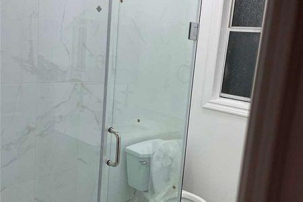 A bathroom featuring a glass-enclosed shower with white marble tile and a window. - 2 - 271 Dunn Avenue, Toronto