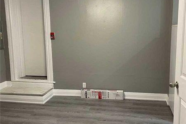 An empty room with gray walls, white trim, a door, and gray laminate flooring. - 2 - 271 Dunn Avenue, Toronto