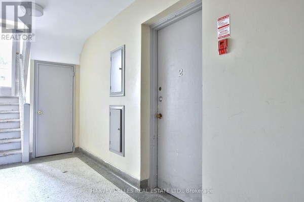Living room with parquet flooring, white built-in bookshelf, and doorways to other rooms. - 2 - 28 Fraserwood Avenue, Toronto