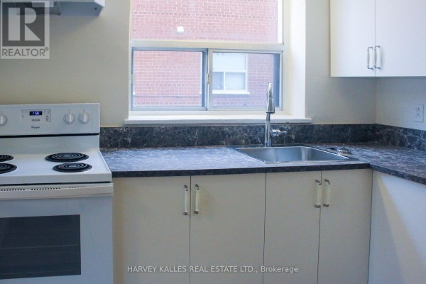 Kitchen with white cabinetry, a double sink, faucet, and a white electric stove. - 2 - 28 Fraserwood Avenue, Toronto