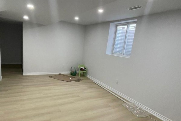Empty room with light wood laminate flooring, white walls, and a small window. - 2 - 29 Dunstable Drive, Whitby