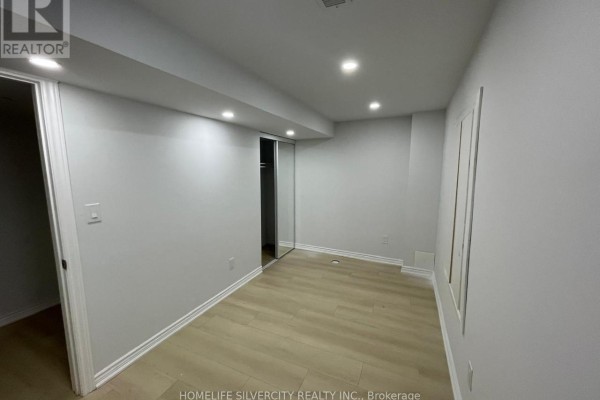 Bedroom with light wood laminate flooring, white walls, and mirrored closet doors. - 2 - 29 Dunstable Drive, Whitby