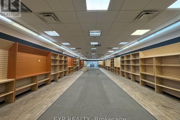Interior view of a large, empty retail space with rows of empty shelving units and wood-look flooring. - 2 - 301 Oxford Street W, London North