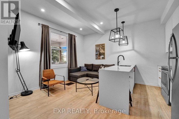Interior view showing living area, kitchen island, and a tall floor lamp. - 2 - 327 Catherine Street, Ottawa