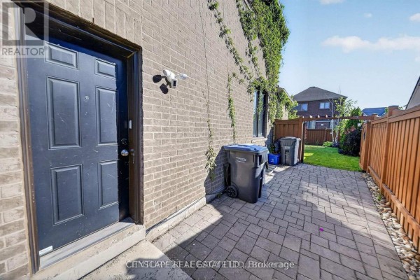 Paved walkway with garbage bins beside a brick house and a wooden fence in the backyard. - 2 - 33 Andretti Crescent, Brampton